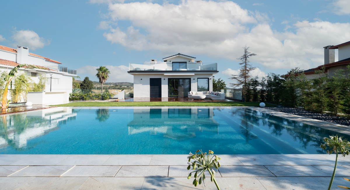 **SEO uyumlu alternatif metin (alt text):** Modern villanın önünde konumlandırılmış, porselen kaplamalı, geniş ve dikdörtgen formda yüzme havuzu; çevresi peyzajla bütünleşmiş estetik havuz tasarımı.