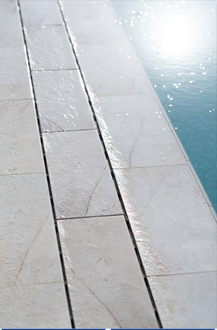 Azulejo porcelánico Serapool en tono beige claro resistente al agua, detalle de textura de piedra natural y superficie antideslizante bajo la luz del día, junto al borde de la piscina.