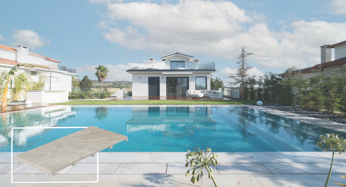 Beige Stone porselen yüzey ve monoblok gizli ızgara detayıyla tasarlanmış havuz kenarı; arka planda modern villa ve yansımalı yüzme havuzu görünümü.